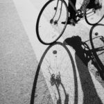 Photo noir et blanc avec un vélo partiellement visible qui projette une ombre sur le sol.