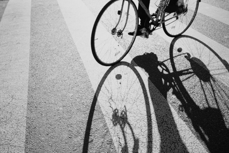 Photo noir et blanc avec un vélo partiellement visible qui projette une ombre sur le sol.